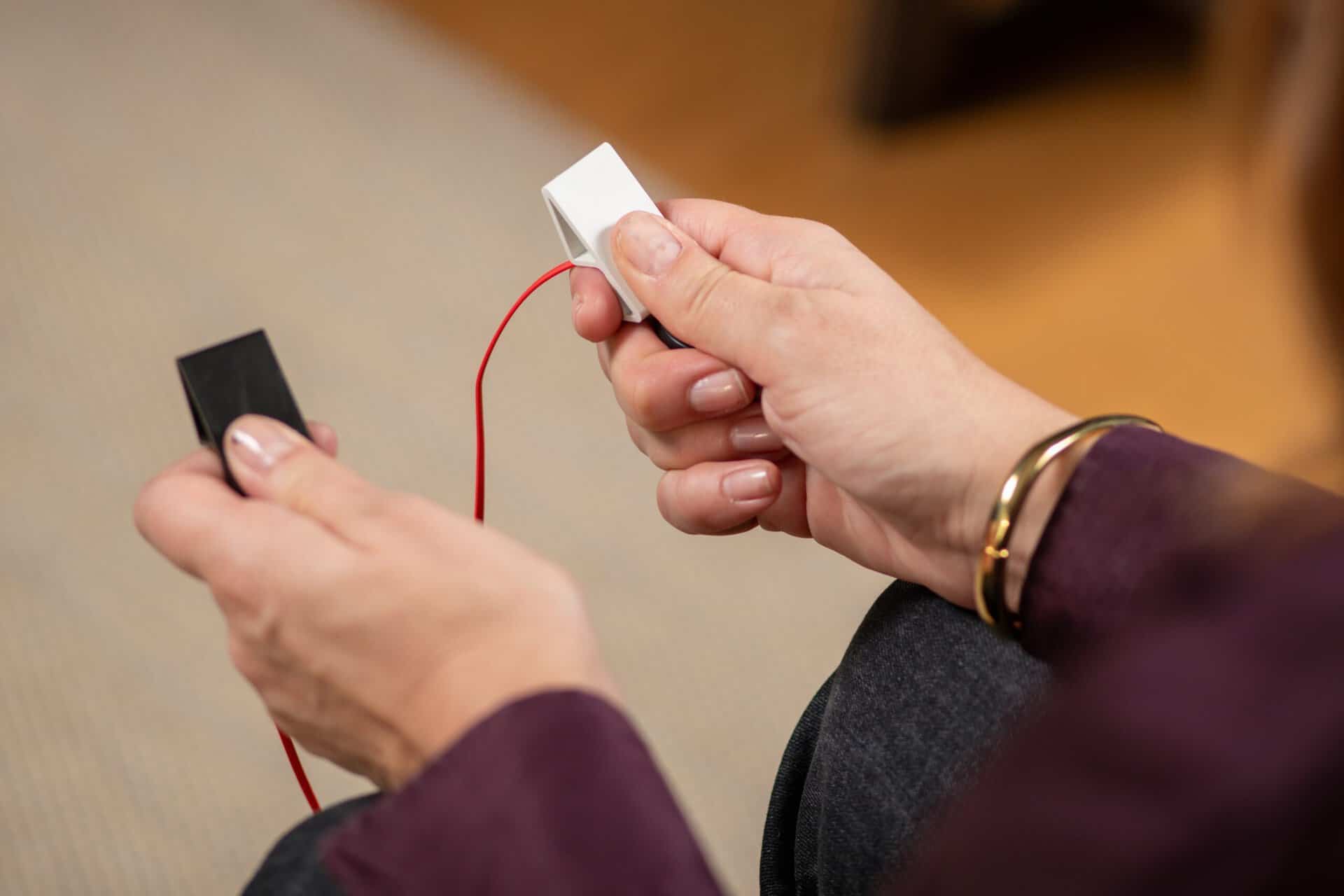 A client's hands holding electronic tactile pulsator buzzers for bilateral stimulation during an EMDR therapy session in Orange County.